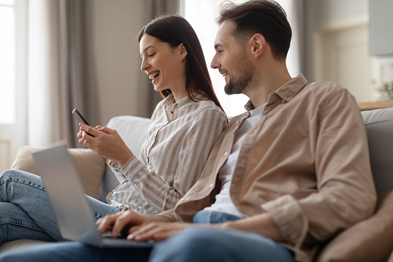 young-couple-using-laptop-and-smartphone Young couple using digital devices, exemplifying modern connectivity in rural homes.